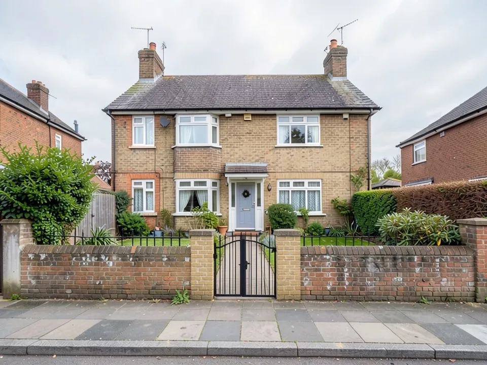 The same house where the old wall now has buff brick piers at the path with a black metal gate, and black railings behind the wall