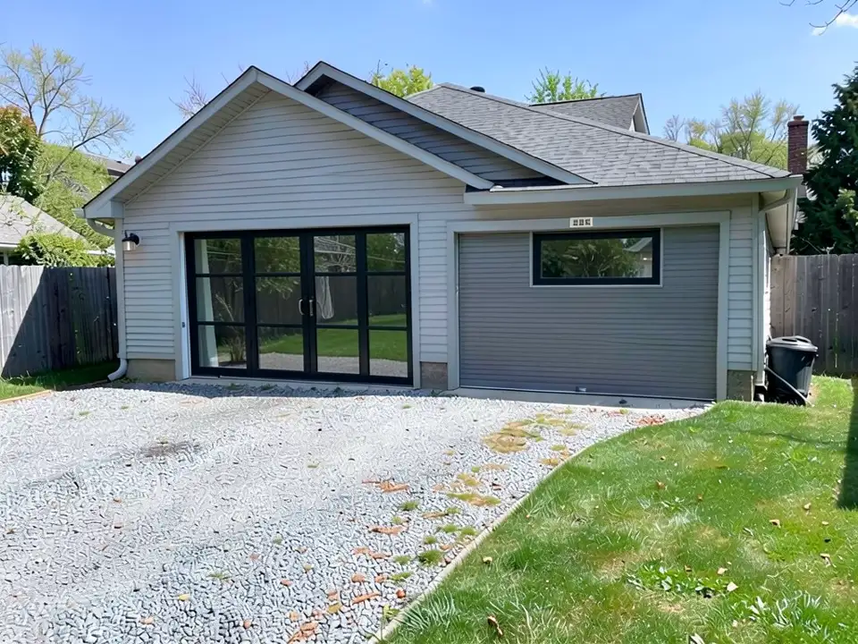 The same garage with the left roll-up door replaced by black-framed glass doors, and a narrow black-framed window set into the upper part of the right roll-up door, which stays in place